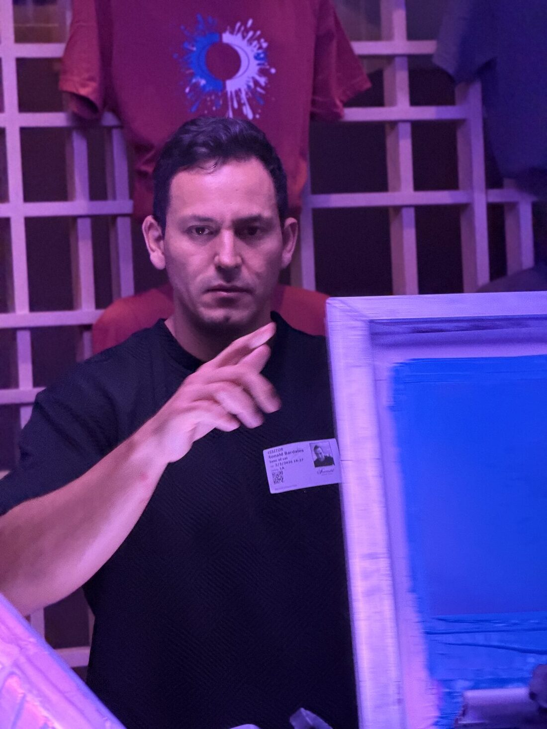 Merch Troop crew member directing guests at a live station under purple event lighting