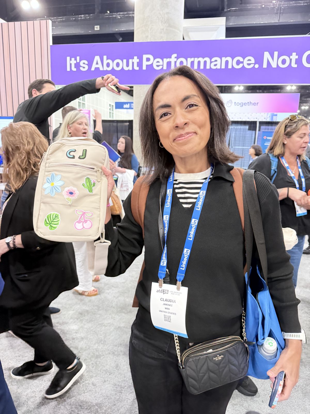 Conference attendee holding a tan crossbody bag customized with C J initials and flower and cactus embroidered patches